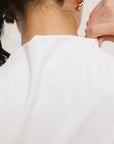 A woman models a white sleeveless dress with a zipper down the front, designed for comfort and movement.