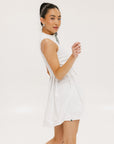 A woman models a white sleeveless dress with a zipper down the front, designed for comfort and movement.