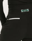 A female model wearing black athletic pants and a long-sleeve black top, standing against a white background.