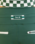A pair of green athletic pants designed for golfing, with a comfortable waistband and a fitted design that enhances the silhouette. The pants are modeled by a woman who is also wearing a checkered top and sneakers.