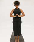 Person wearing black high-waisted pants with a white logo on a light gray background