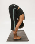 Person wearing black high-waisted pants with a white logo on a light gray background