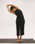 Person wearing black high-waisted pants with a white logo on a light gray background