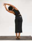 Person wearing black high-waisted pants with a white logo on a light gray background