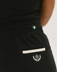 Person wearing black high-waisted pants with a white logo on a light gray background