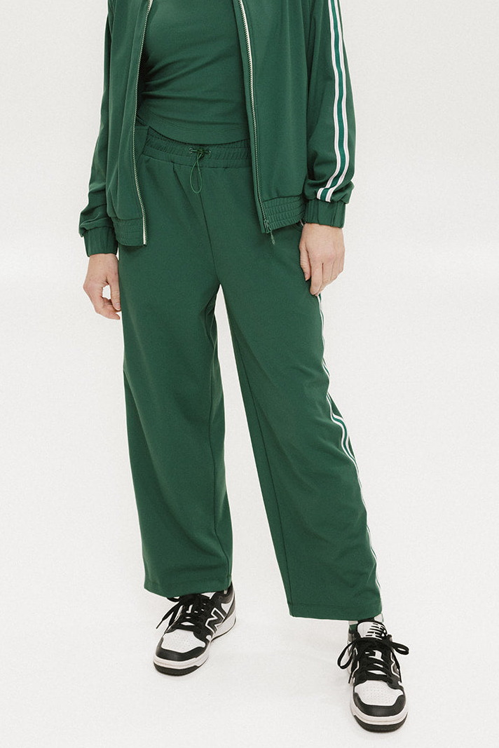 Person wearing a green tracksuit with white stripes on a white background