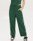 A person standing wearing green Bronson pants with a drawstring waist, green top, and black and white sneakers.
