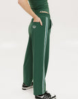 A person standing wearing green Bronson pants with a drawstring waist, green top, and black and white sneakers.