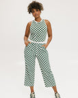 A pair of green checkered pants with a relaxed fit and pockets, worn by a model in a matching checkered top and sneakers.