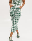 A pair of green checkered pants with a relaxed fit and pockets, worn by a model in a matching checkered top and sneakers.