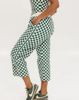 A pair of green checkered pants with a relaxed fit and pockets, worn by a model in a matching checkered top and sneakers.