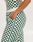 A person standing, wearing green and white checkered pants with a modern fit and soft fabric.