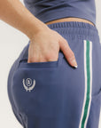 A person standing wearing indigo blue track pants with a drawstring waist.