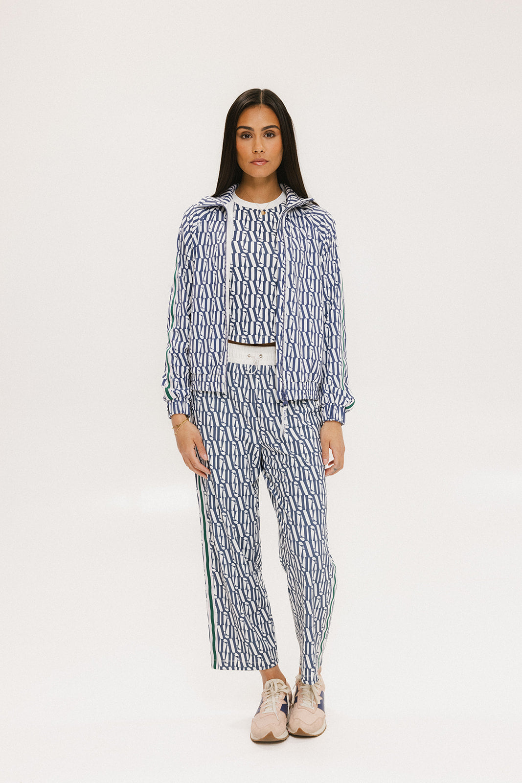 A person standing wearing the Bronson Pant in indigo color, which features a geometric pattern. The pants are casual and the person is paired them with a matching top and pink sneakers.