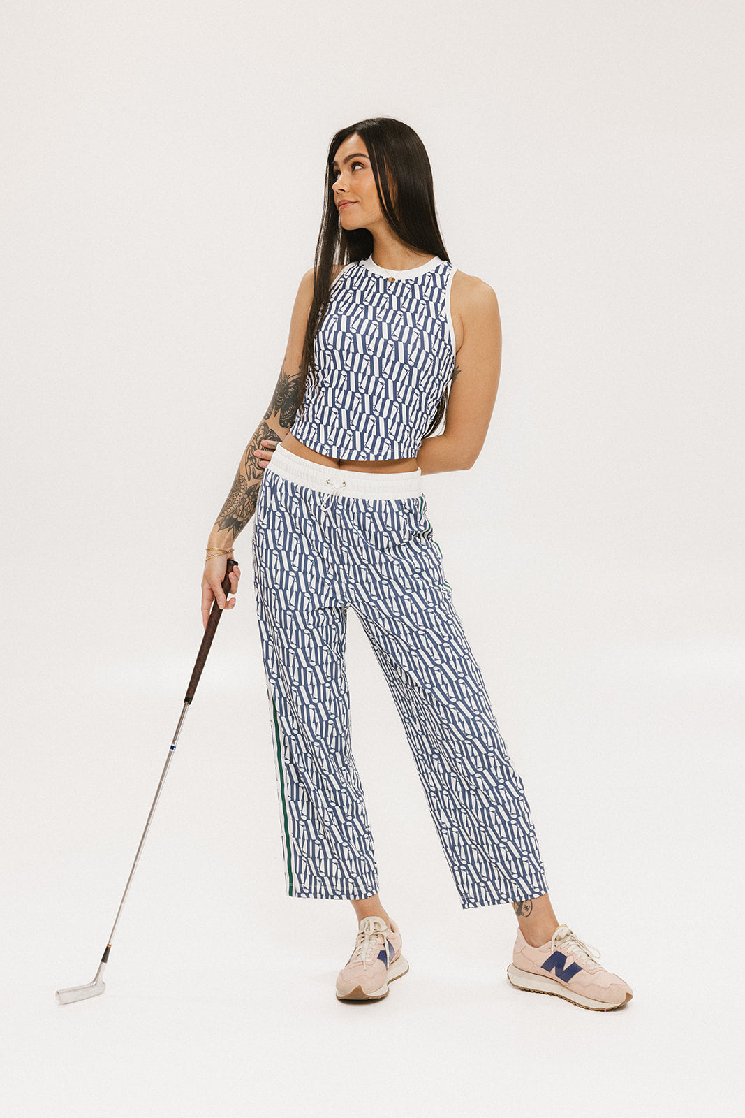 A person standing wearing the Bronson Pant in indigo color, which features a geometric pattern. The pants are casual and the person is paired them with a matching top and pink sneakers.
