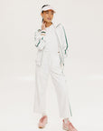 A pair of white Bronson pants with a subtle stripe detail on the side, paired with a white top and pink sneakers.