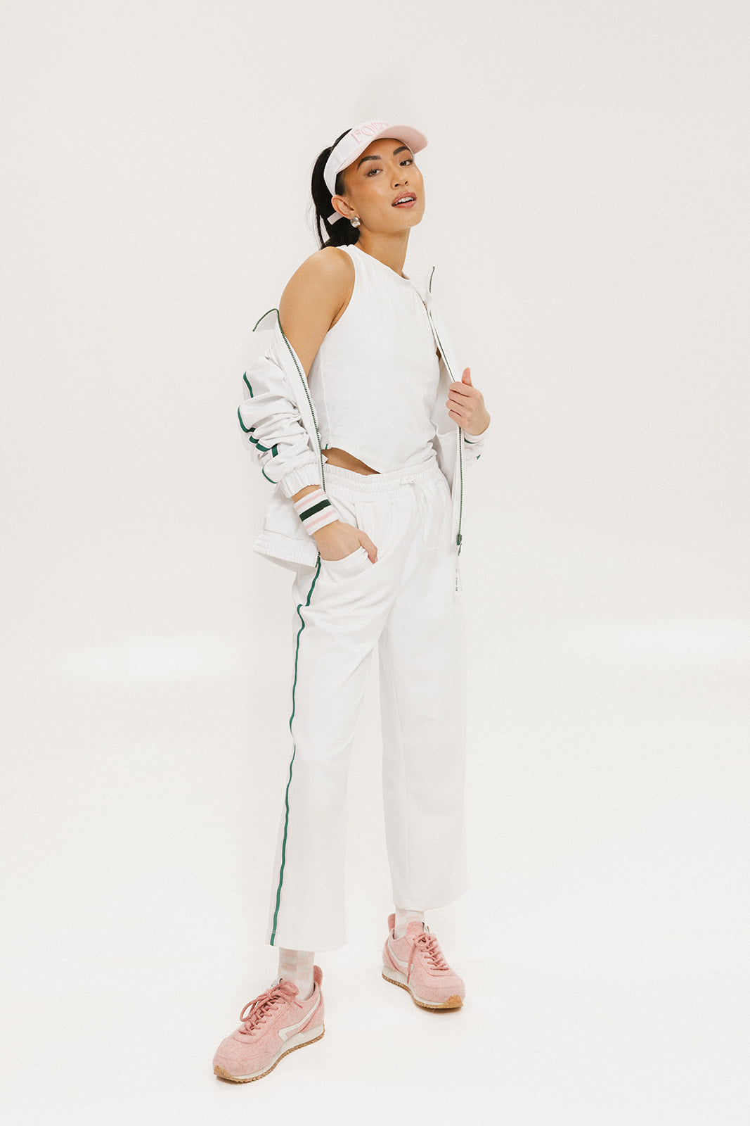 A pair of white Bronson pants with a subtle stripe detail on the side, paired with a white top and pink sneakers.