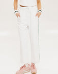 A pair of white Bronson pants with a subtle stripe detail on the side, paired with a white top and pink sneakers.