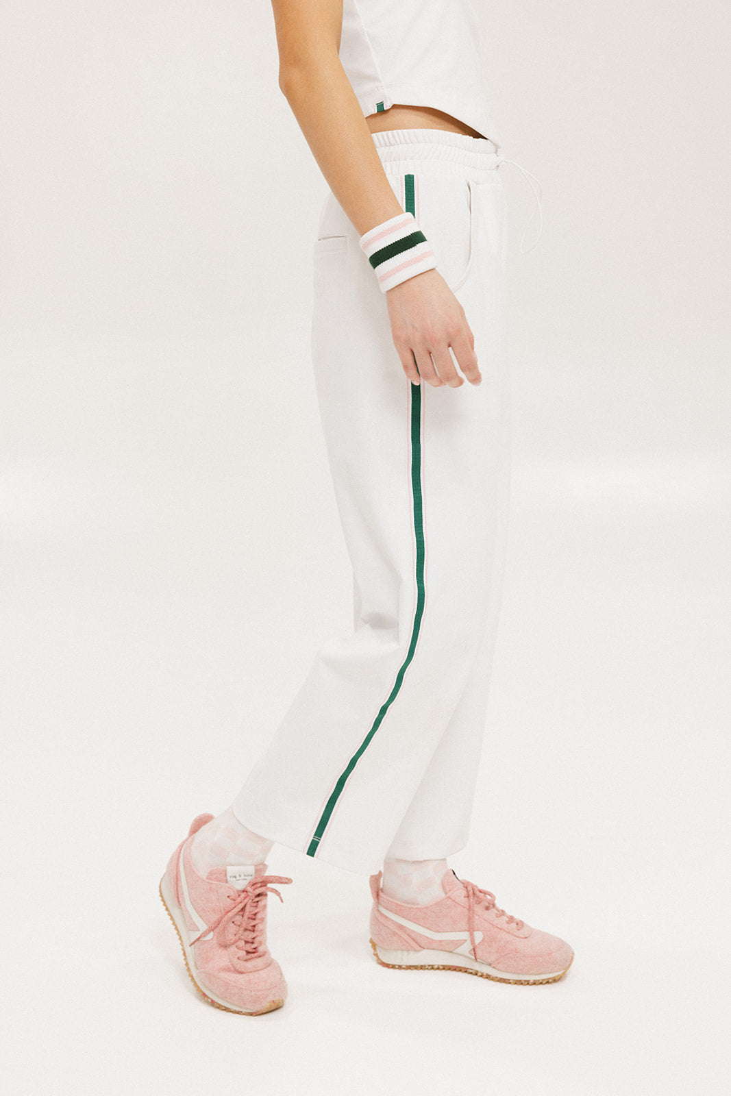 A pair of white Bronson pants with a subtle stripe detail on the side, paired with a white top and pink sneakers.