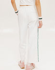 A pair of white Bronson pants with a subtle stripe detail on the side, paired with a white top and pink sneakers.