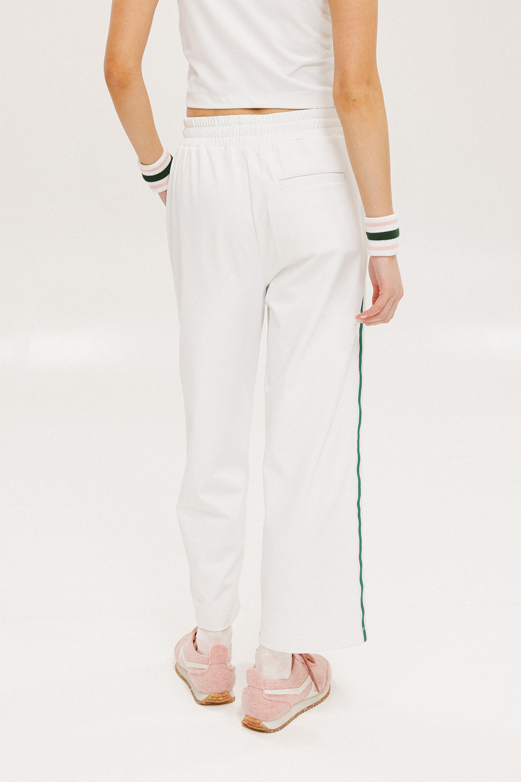A pair of white Bronson pants with a subtle stripe detail on the side, paired with a white top and pink sneakers.