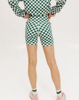 A person wearing green and white checkered biddy shorties and a matching checkered golf jacket, standing against a white background.