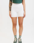 A person wearing white shorts and green shoes.