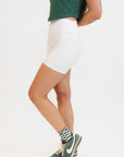 A person wearing white biddy shorties paired with a green lillee tank.