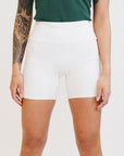 A person wearing white biddy shorties paired with a green lillee tank.
