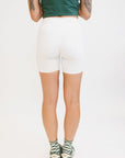 A person wearing white biddy shorties paired with a green lillee tank.