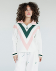 A woman wearing a white sweatshirt with pink and green geometric patterns and a quarter-zip design.