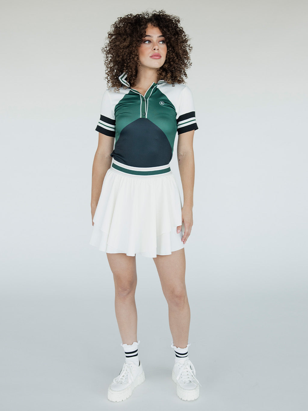 A woman wearing a green, black, and white striped Betty Polo shirt with a preppy collar.
