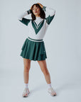 A person wearing a green and pink Micky Quarter Zip golf shirt paired with a green skirt.