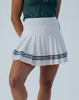 White pleated skirt with blue stripes worn by a person on a plain background