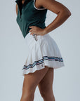 Person wearing a green top and white skirt with blue stripes on a plain background
