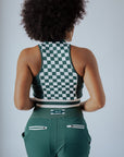 A woman wearing a green checkered full zip tank top with a mock neck.