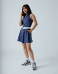 A woman wearing a navy blue ribbed golf dress with a high collar and short sleeves, featuring a full zipper in the front.