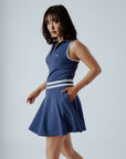 A woman wearing a navy blue ribbed golf dress with a high collar and short sleeves, featuring a full zipper in the front.
