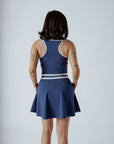 A woman wearing a navy blue ribbed golf dress with a high collar and short sleeves, featuring a full zipper in the front.