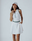 A woman wearing a white ribbed sleeveless golf dress with a high collar and a full front zipper.