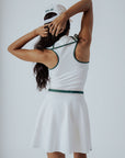 A woman wearing a white ribbed sleeveless golf dress with a high collar and a full front zipper.