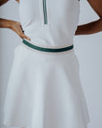 A woman wearing a white ribbed sleeveless golf dress with a high collar and a full front zipper.