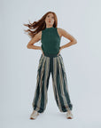 A woman wearing a green sleeveless tank top with a crew neckline and striped pants.