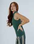 A woman wearing a green sleeveless tank top with a crew neckline and striped pants.