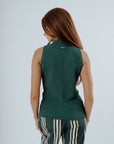 A woman wearing a green sleeveless tank top with a crew neckline and striped pants.