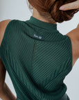 A woman wearing a green sleeveless tank top with a crew neckline and striped pants.