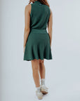A model wearing a green knee-length skirt with a tie-belt and shorties underneath. The skirt has a textured fabric.