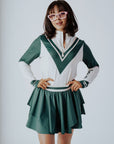 A person wearing a green and pink Micky Quarter Zip golf shirt paired with a green skirt.