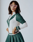 A person wearing a green and pink Micky Quarter Zip golf shirt paired with a green skirt.