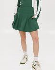 A person wearing a high-waisted green skirt with a solid pattern, paired with a white top and light-colored shoes.